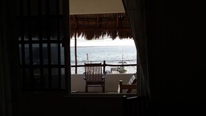 A balcony with a view of the sea, a chair, and a table with a plant. - Hotel Punta Ponto (Río Lagartos)