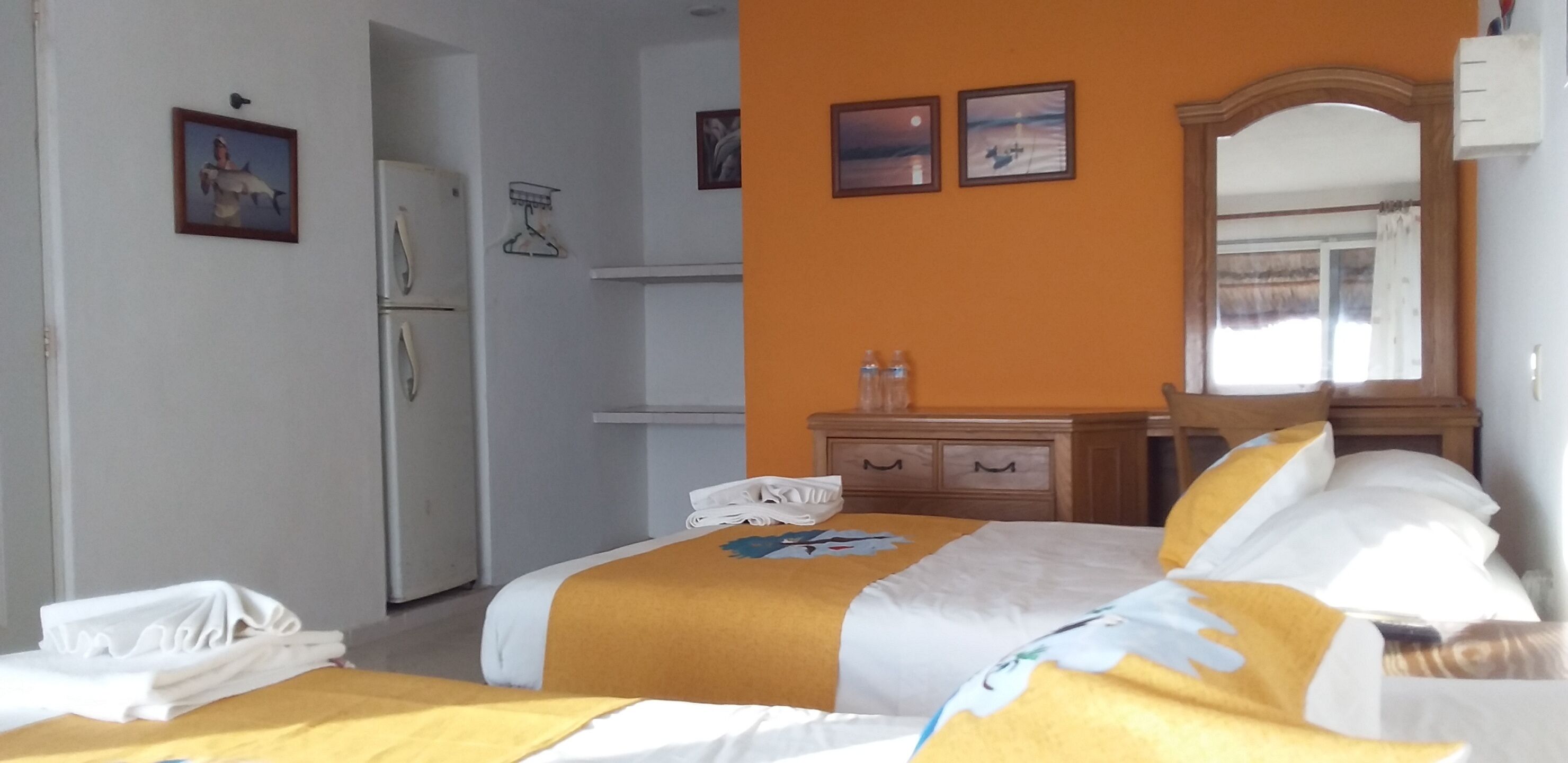 A hotel room with a bed, a dresser, a mirror, and a door.