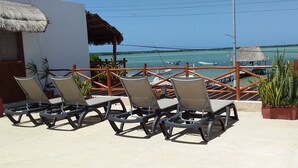 A terrace with lounge chairs and a view of the sea. - Hotel Punta Ponto (Río Lagartos)