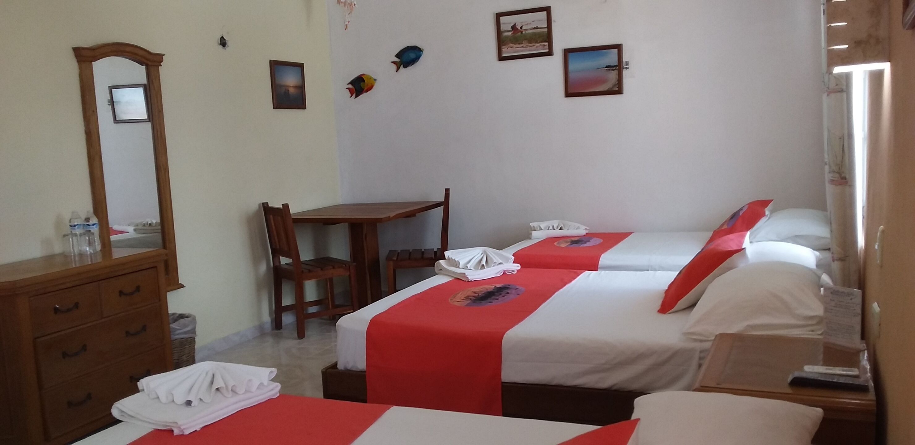 A hotel room with two beds, a wooden desk, a chair, a dresser, and a mirror.