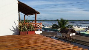 A wooden staircase leading to a covered area with potted plants, overlooking a marina with boats and a clear view of the water. - Hotel Punta Ponto (Río Lagartos)