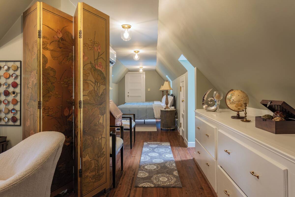 A bedroom with a bed, a chair, a dresser, a globe, and a lamp.