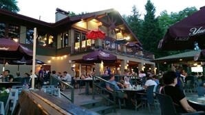 Un restaurante al aire libre con varias mesas y sillas, sombrillas y un edificio con balcón.