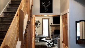 Una escalera con barandillas de madera que conduce a una sala de estar con chimenea, un sofá y una mesa de centro.