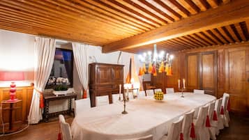 Une salle à manger avec un plafond en bois, un lustre et une table dressée pour le repas.