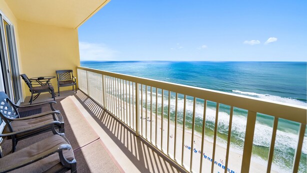 A balcony with a view of the ocean, featuring two chairs and a small table.