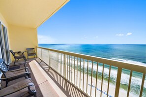 A balcony with a view of the ocean, featuring two chairs and a small table.