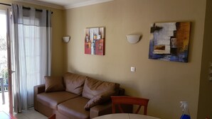 Een woonkamer met een bruine bank, een tafel en twee wandlampen.