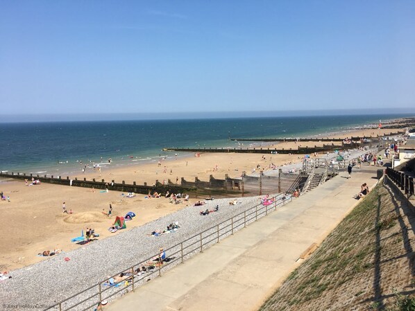 A beach with a promenade, sandy areas, and a rocky beach section.