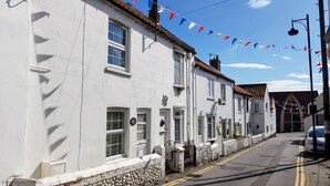 A row of white buildings with multiple windows and doors, a stone wall, and a clear sky. - Crab Cottage - sleeps 4 guests  in 2 bedrooms (Sheringham)