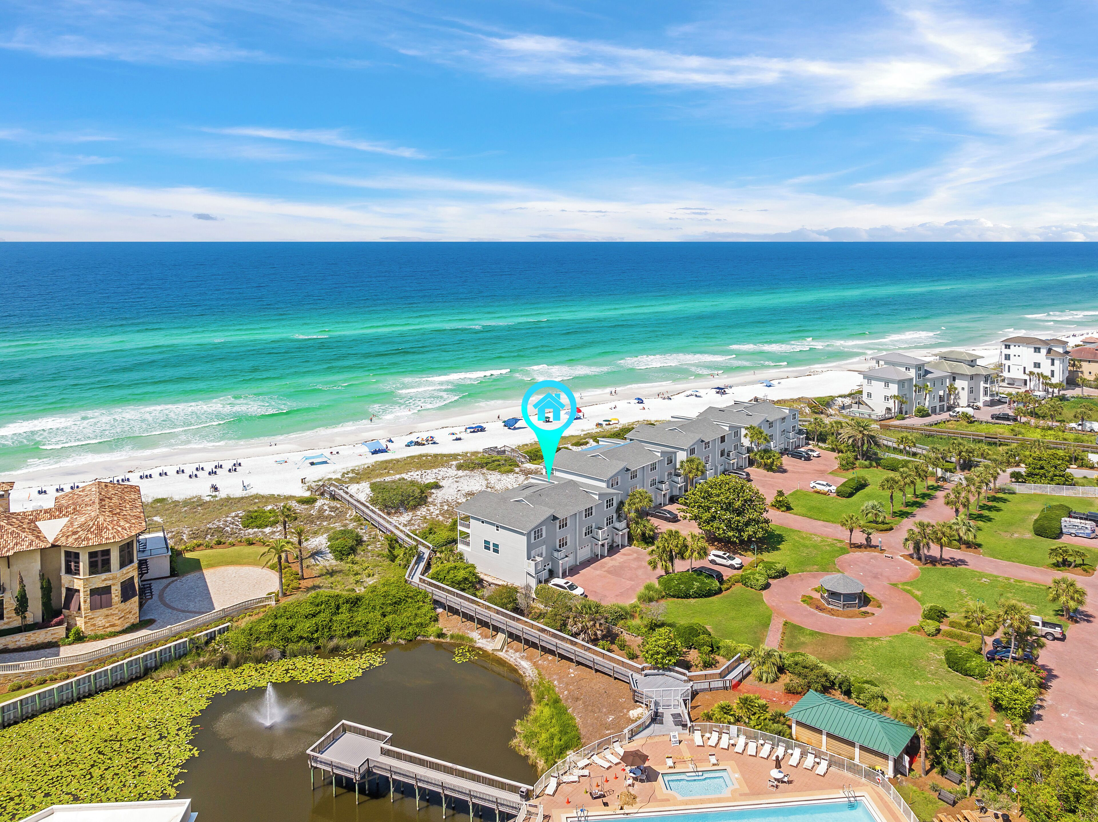 A coastal resort with a beach, a swimming pool, and a small pond with lily pads.