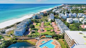 Un complejo turístico costero con una piscina grande, villas frente a la playa y un jardín bien cuidado.