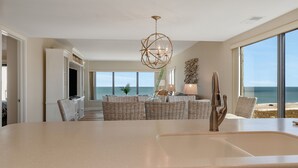 Una cocina moderna con una isla grande, un lavaplatos empotrado y una zona de comedor con mobiliario de mimbre.