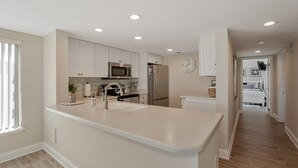 Una cocina moderna con armarios blancos, electrodomésticos de acero inoxidable y una isla central.