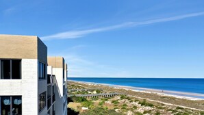 Un edificio moderno con amplios ventanales que dan a una playa y al océano.