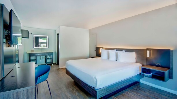 Una moderna camera d'albergo con un ampio letto, una scrivania e una televisione.