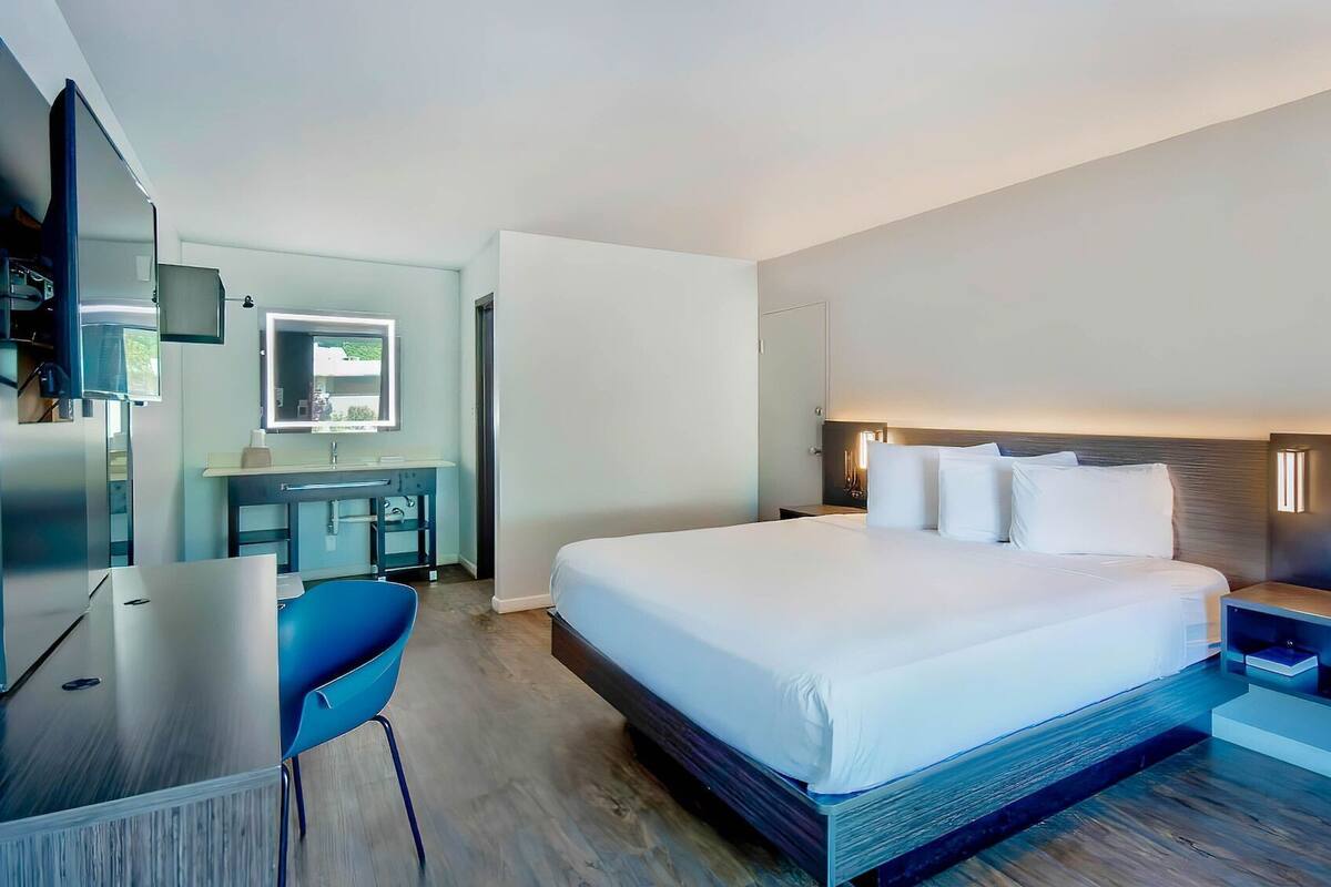Ein modernes Hotelzimmer mit einem großen Bett, einem Schreibtisch und einem Fernseher.