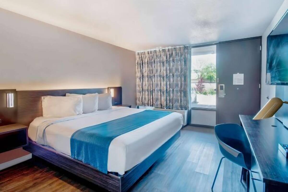 Ein modernes Hotelzimmer mit einem großen Bett, einem Schreibtisch und einem Fernseher.