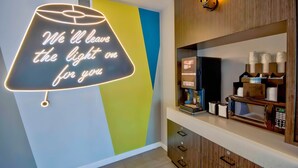 Un interno moderno con un neon che riporta la scritta: 'Vi terremo la luce accesa'.