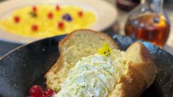 A plate with a slice of bread topped with a creamy spread and red berries.