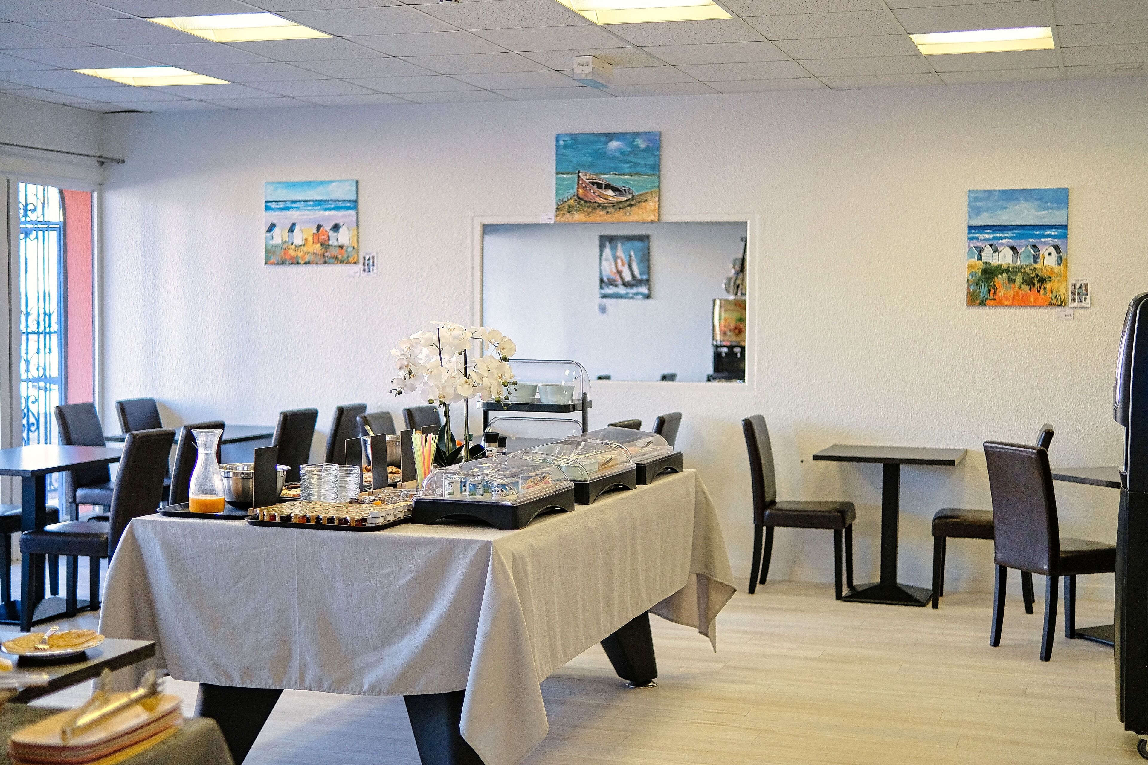 A dining area with a buffet table, chairs, and artwork on the walls.