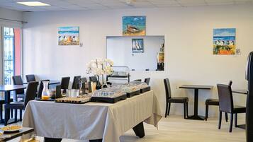 A dining area with a buffet table, chairs, and artwork on the walls.