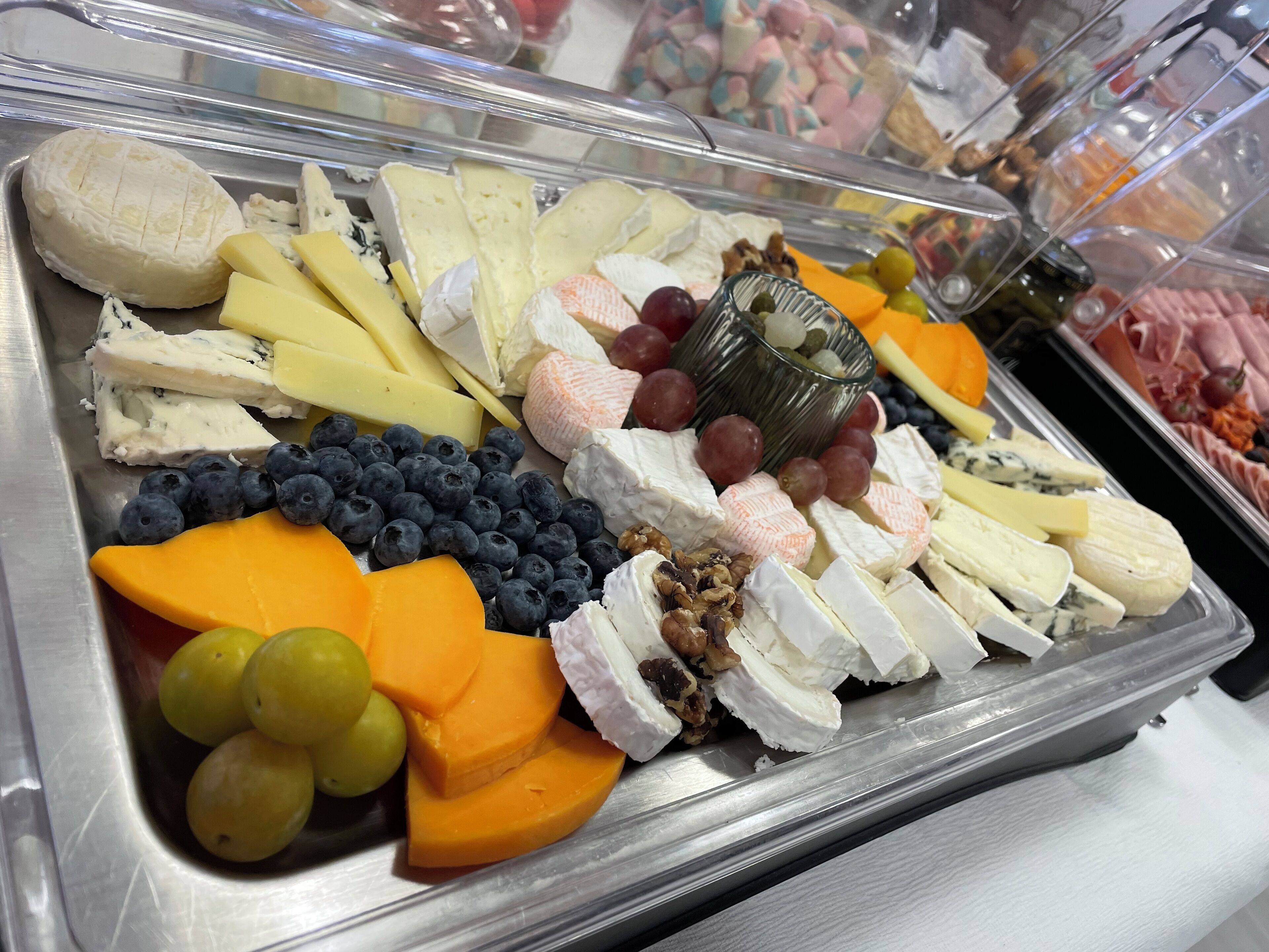 Un bufé con diversos quesos, frutas y frutos secos.