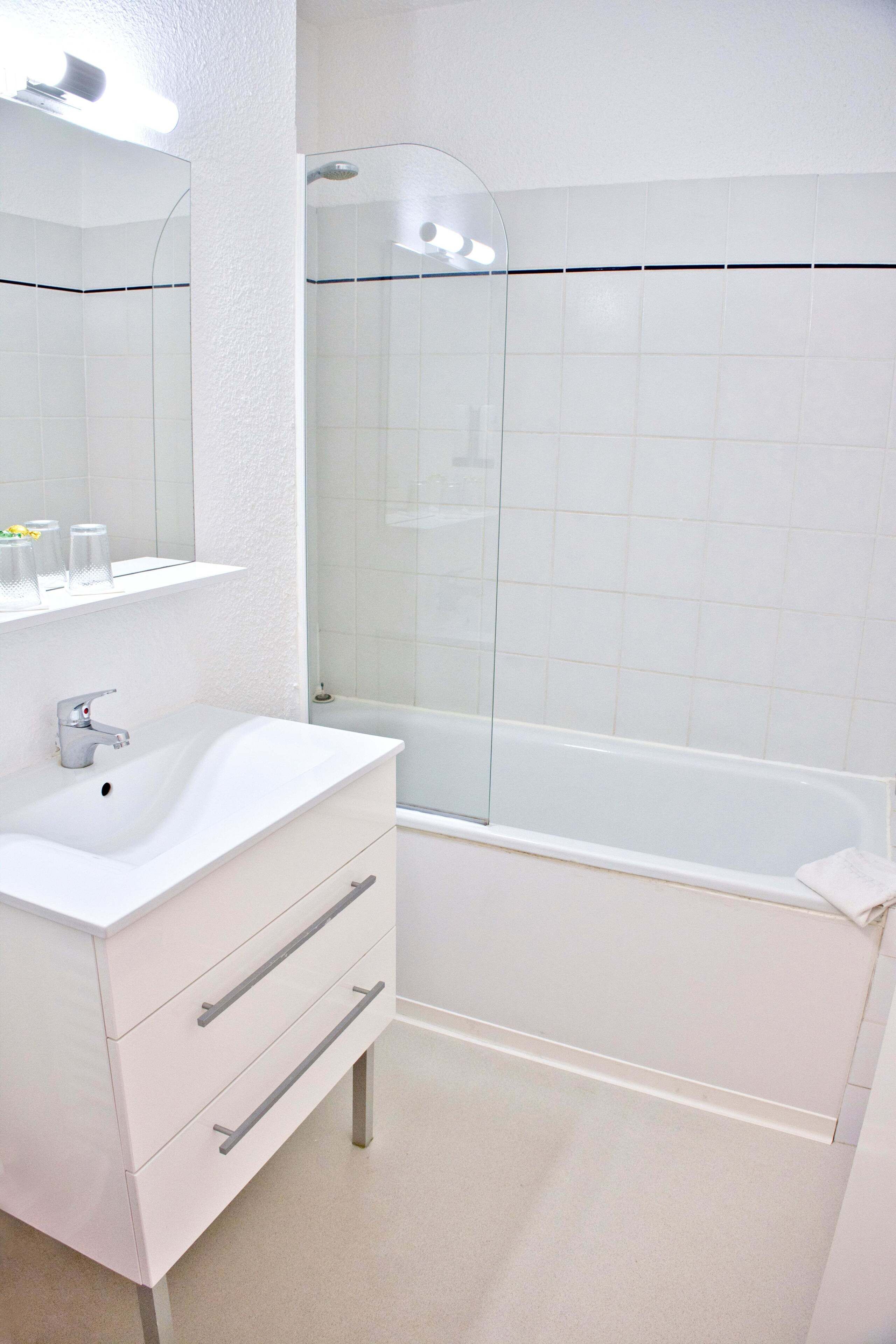 Ein modernes Badezimmer mit Waschbecken, Spiegel und Dusche.
