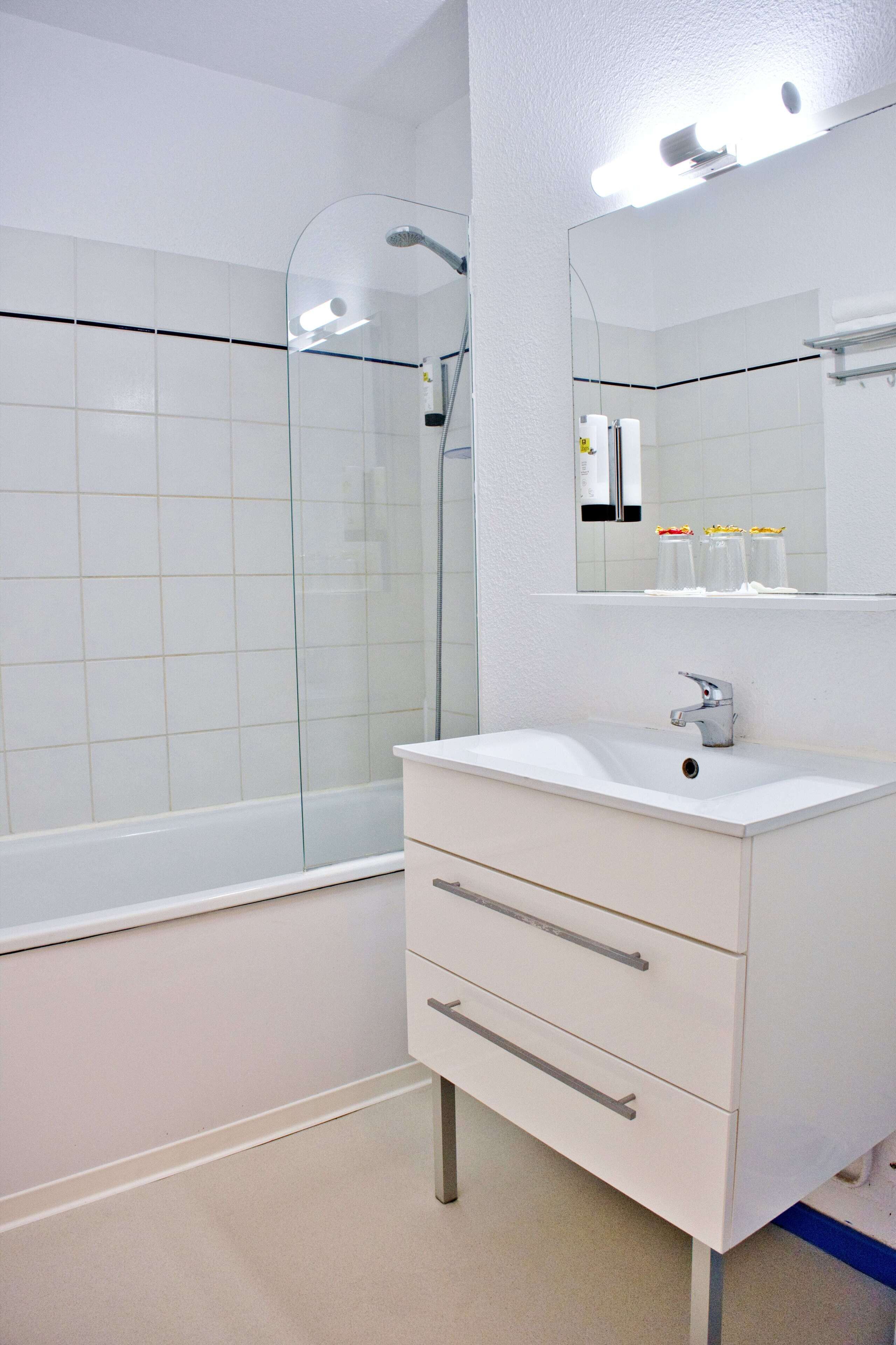A modern bathroom with a glass-enclosed shower, a white sink, and a mirror above it.