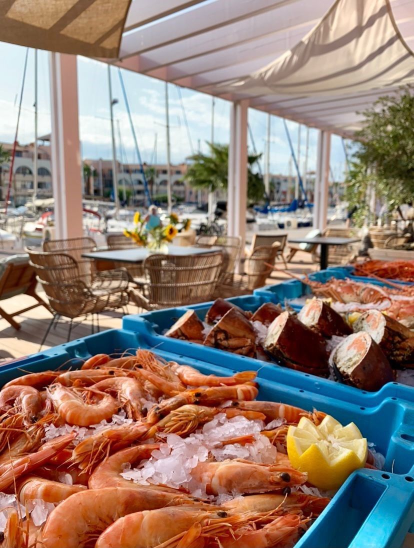 A seafood display at a seaside restaurant with tables and chairs under a canopy.