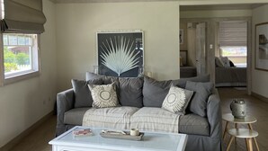 Ein Wohnzimmer mit grauem Sofa, einem weißen Couchtisch und einem gewebten Korb.
