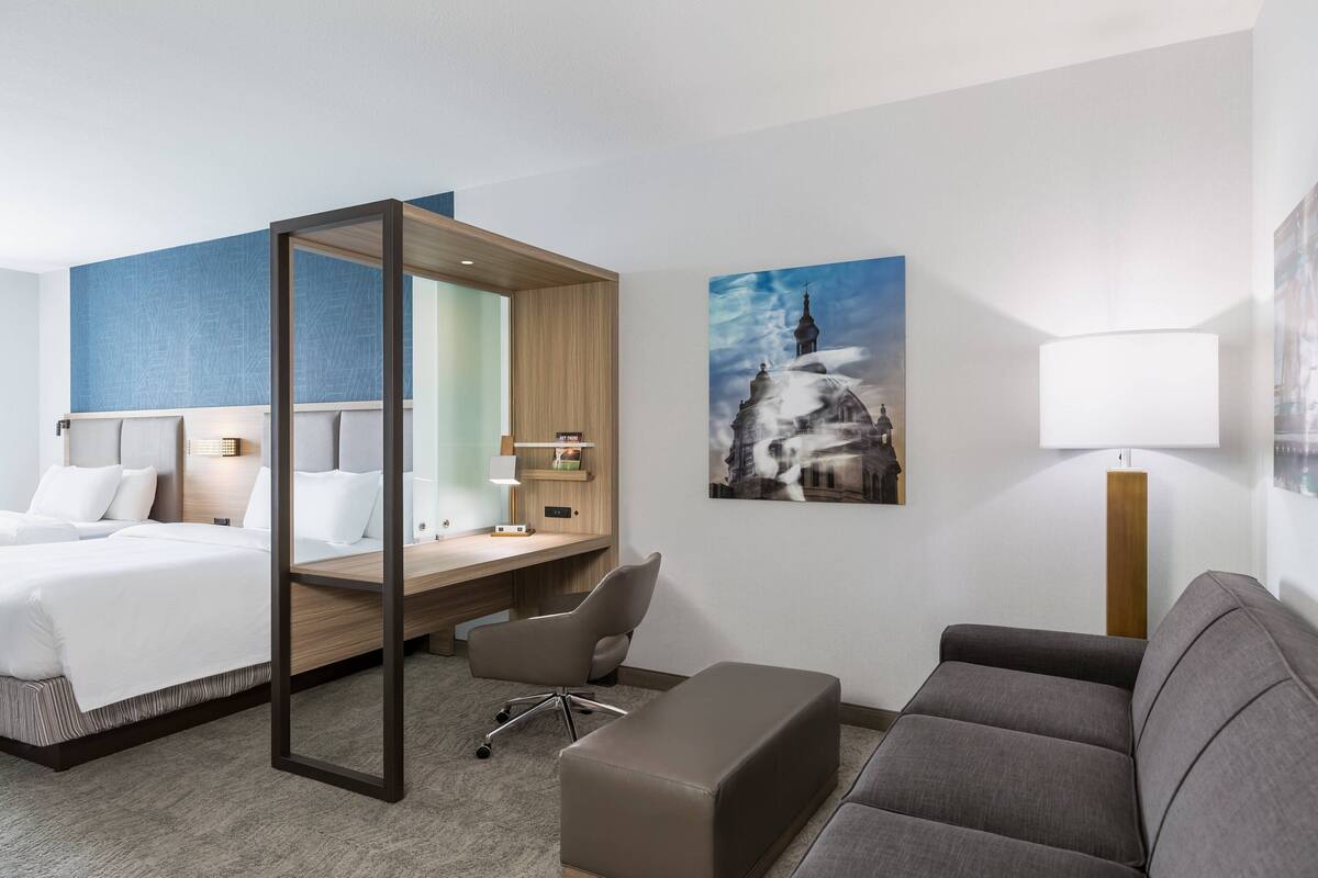 A hotel room with a bed, desk, chair, and couch.