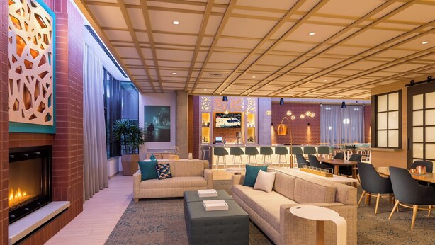 A modern lounge area with sofas, a fireplace, a bar, and a seating area with tables and chairs.