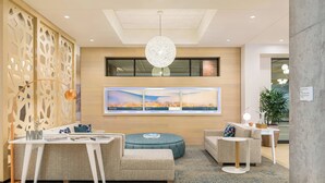 A modern lobby with a seating area, a large artwork on the wall, and a sign indicating room types.
