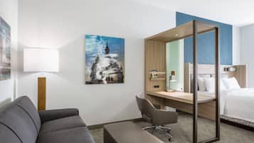 Ein Hotelzimmer mit Sofa, Schreibtisch, Sessel und Bett.