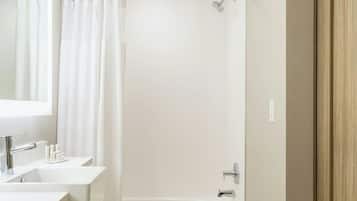 Un baño moderno con bañera, dos lavamanos y un mueble de tocador de madera.