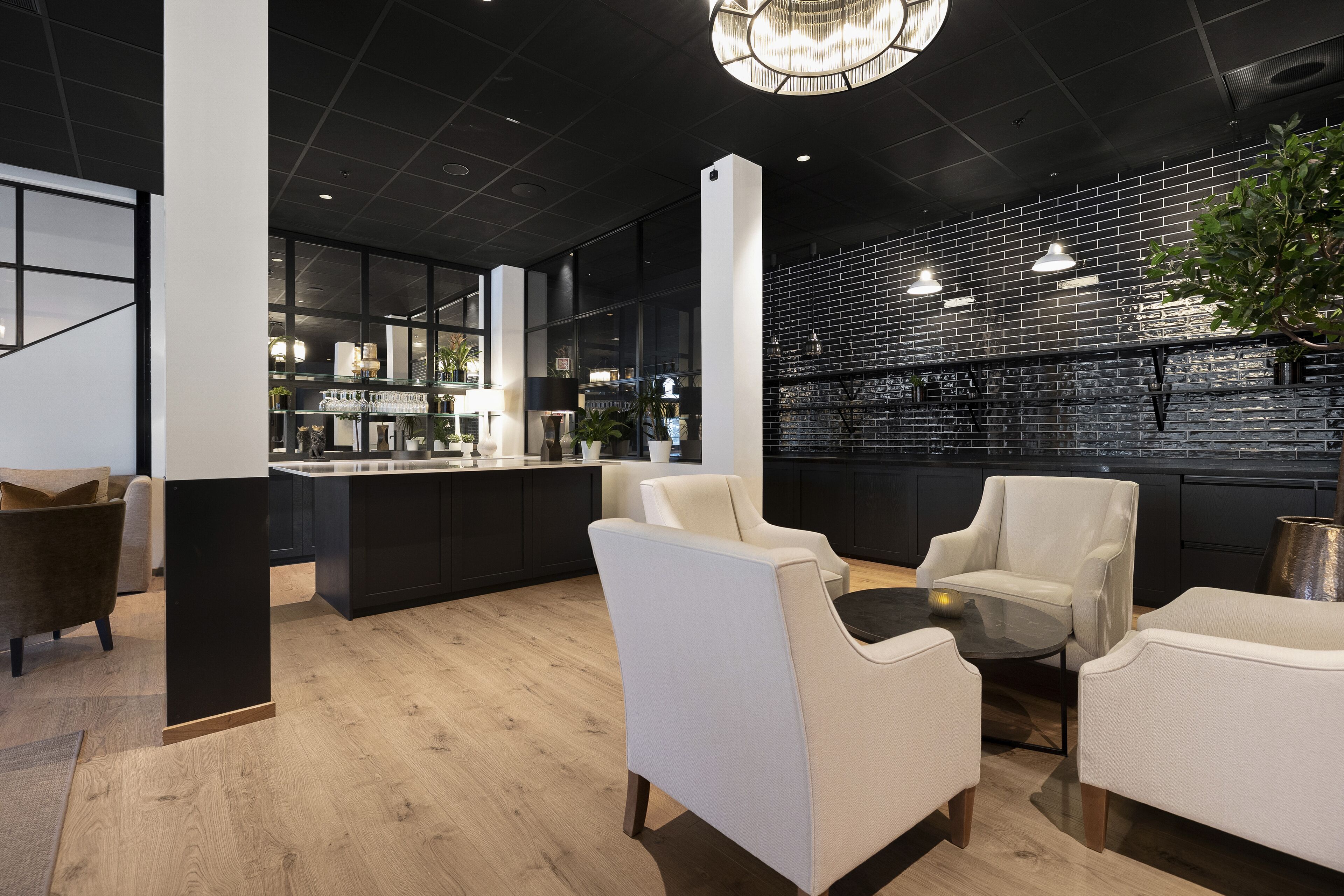 Un interior moderno con pared de ladrillo negro, sillas de cuero blanco y suelo de madera.