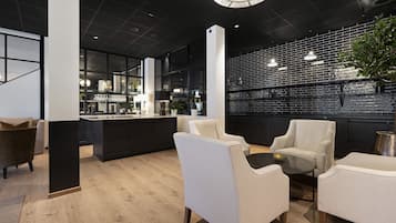 Un interior moderno con pared de ladrillo negro, sillas de cuero blanco y suelo de madera.