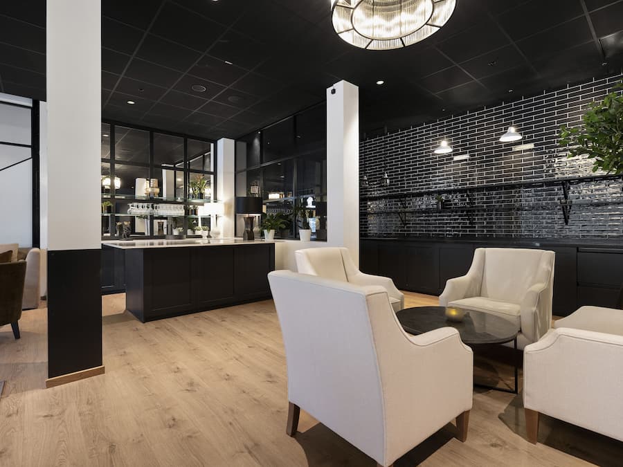 Un interior moderno con pared de ladrillo negro, sillas de cuero blanco y suelo de madera.