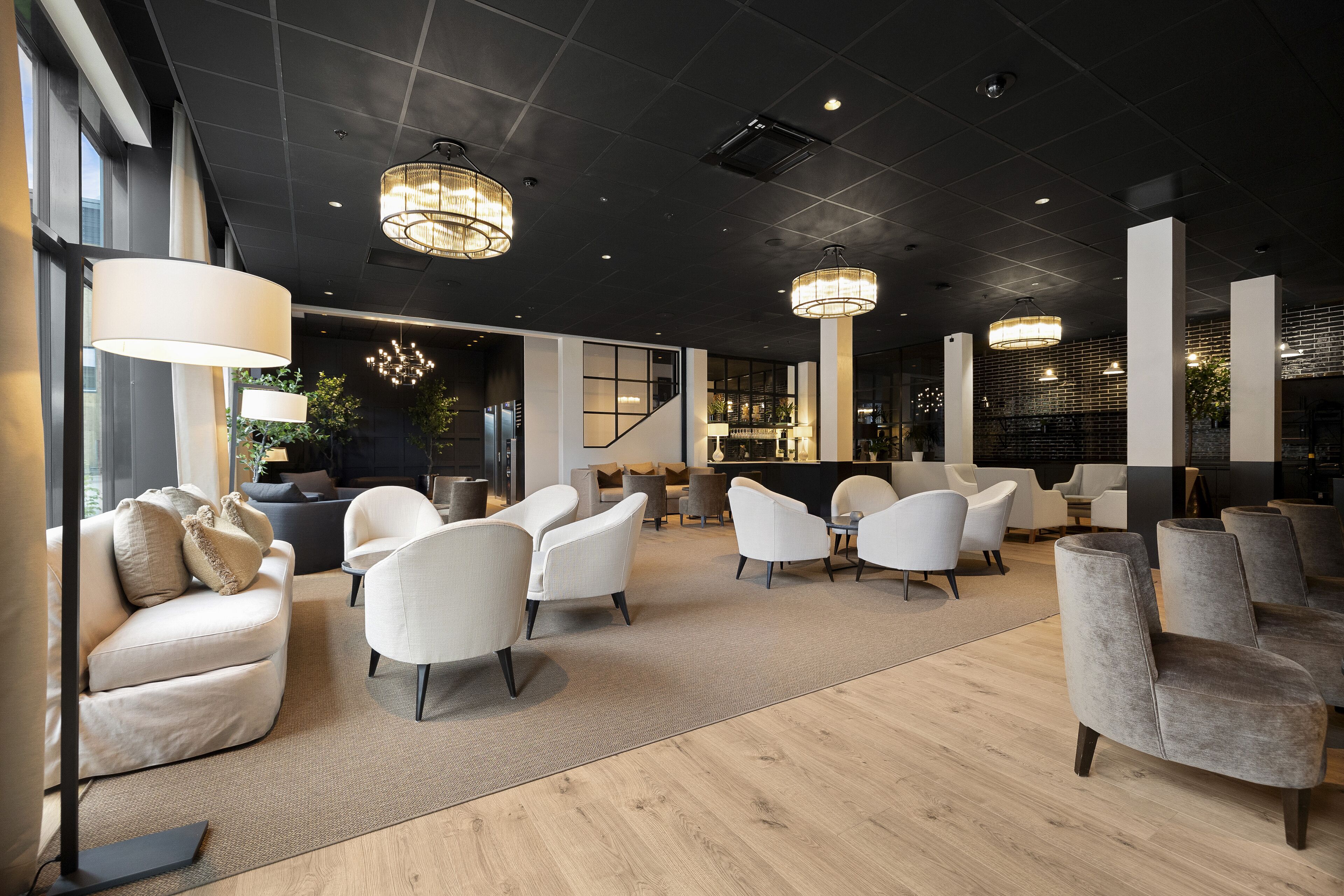 A modern interior with a seating area, large windows, and contemporary lighting fixtures.