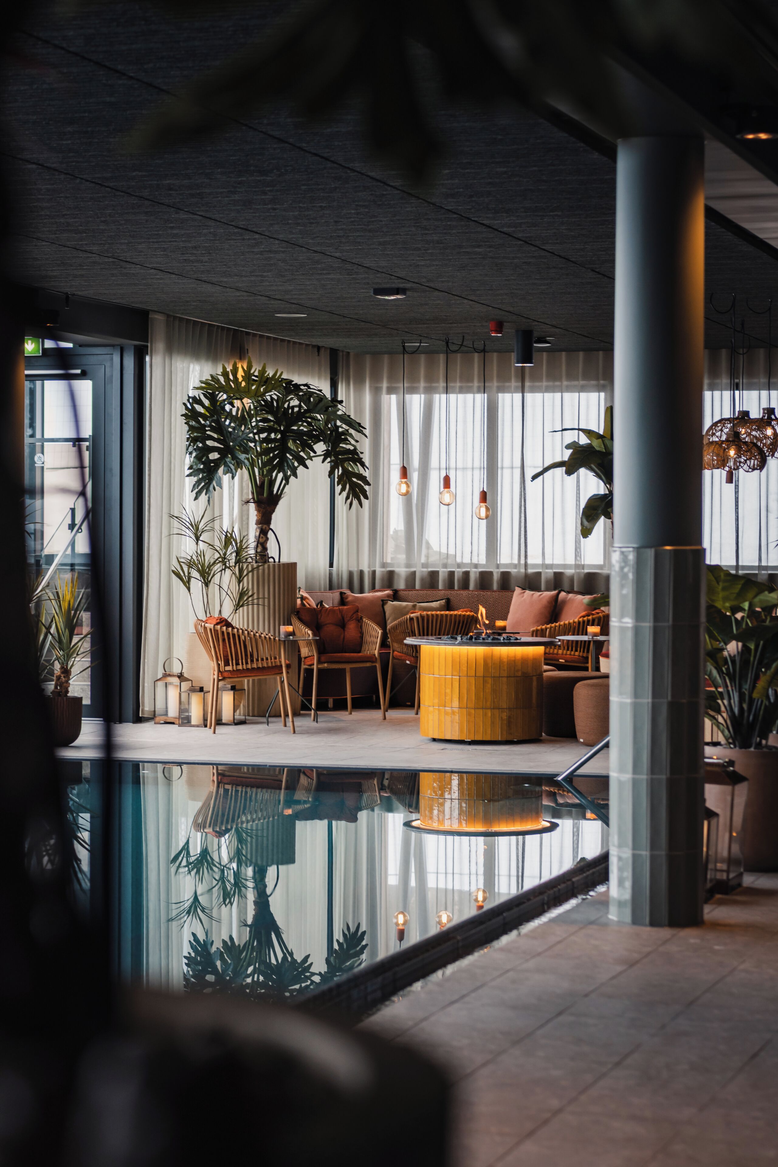 Un área de descanso moderna con piscina, asientos y plantas en macetas.