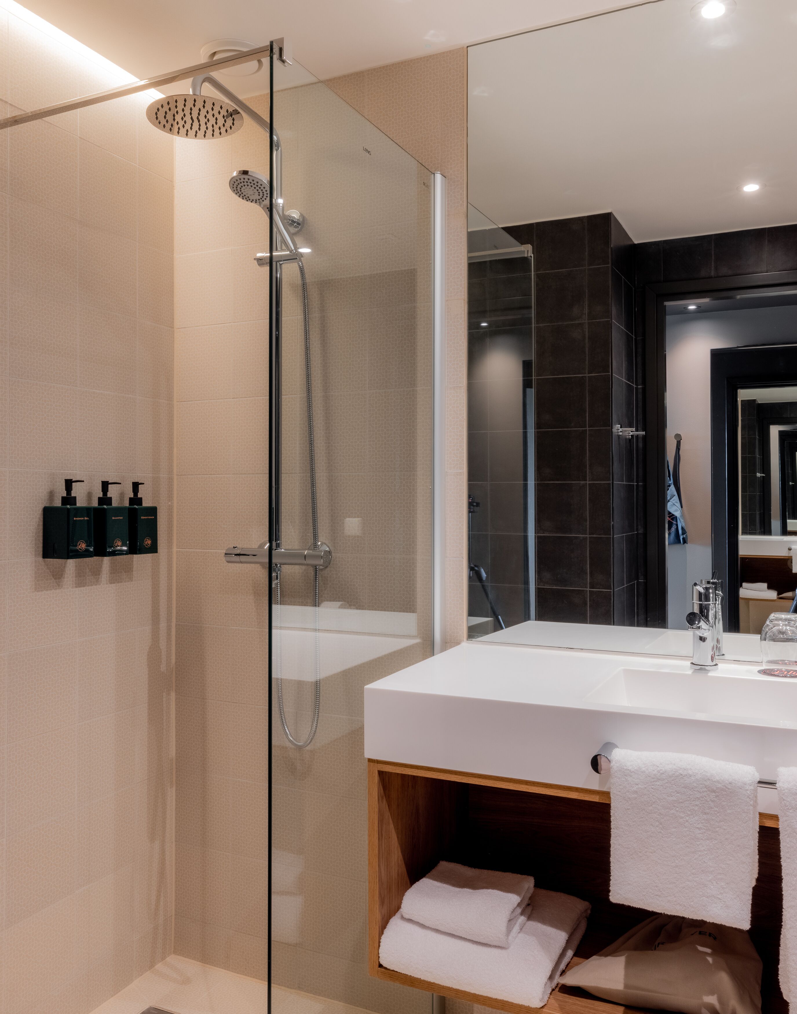 A modern bathroom with a glass-enclosed shower, a white sink, and a large mirror.