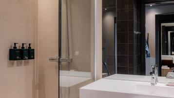A modern bathroom with a glass-enclosed shower, a white sink, and a large mirror.