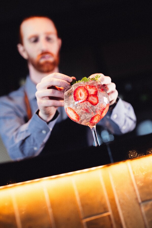 A person holding a cocktail glass with ice and strawberries.