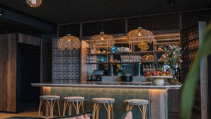 A bar area with wicker stools, a bar counter, and hanging light fixtures. - Lily Country Club (Ullensaker)