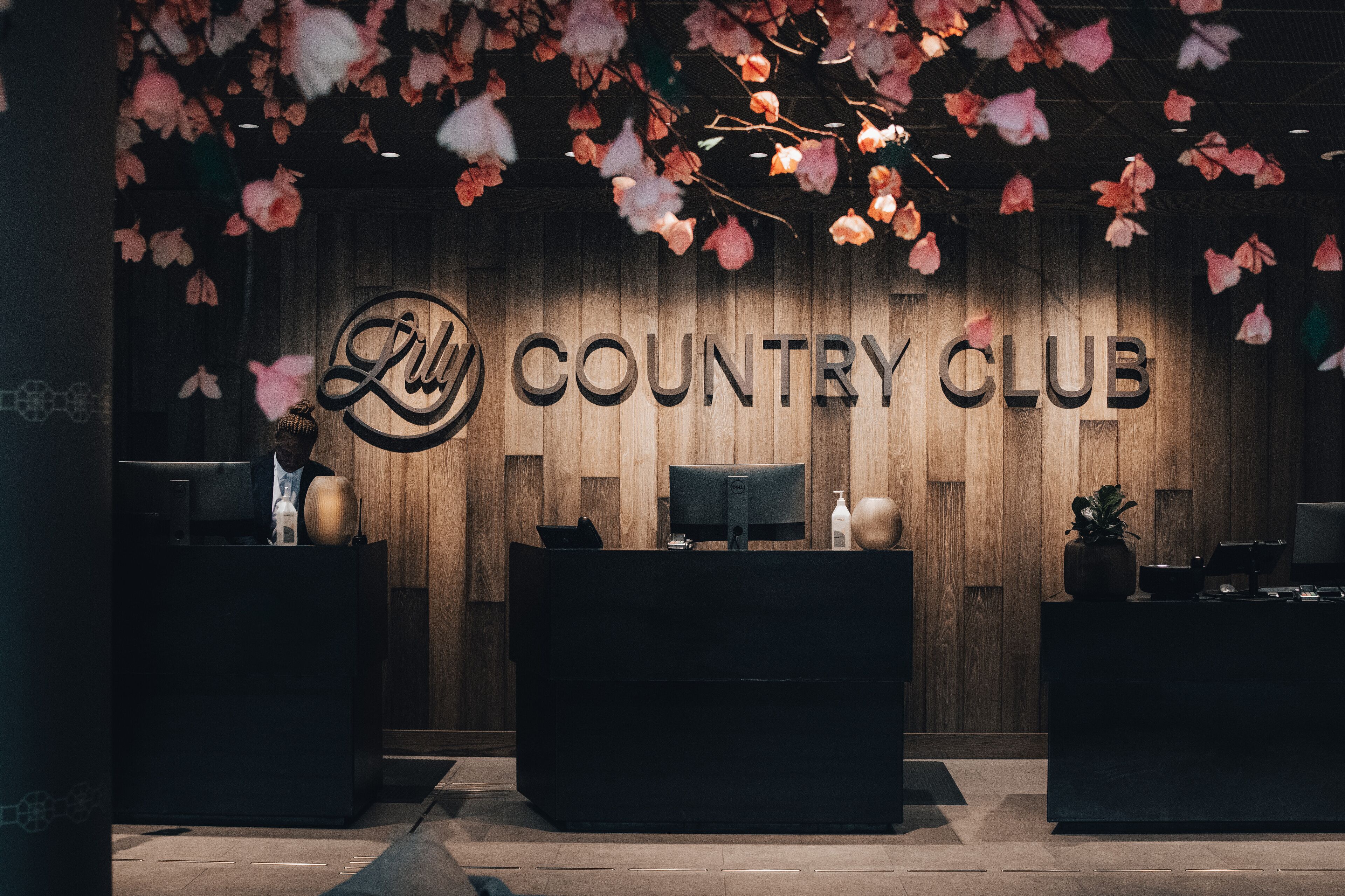 A reception desk with a wooden backdrop and the text "Lilly Country Club".