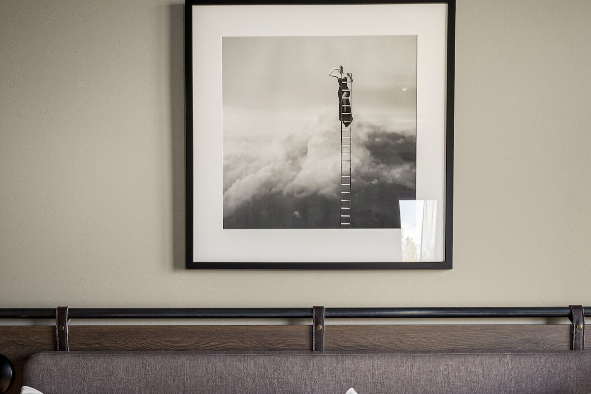 A neatly made bed with white linens and a framed picture above it.