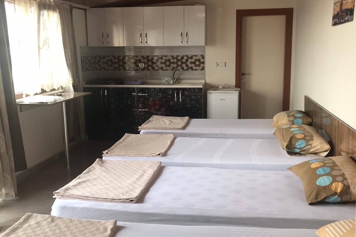 A room with two beds, a kitchenette, and a door.