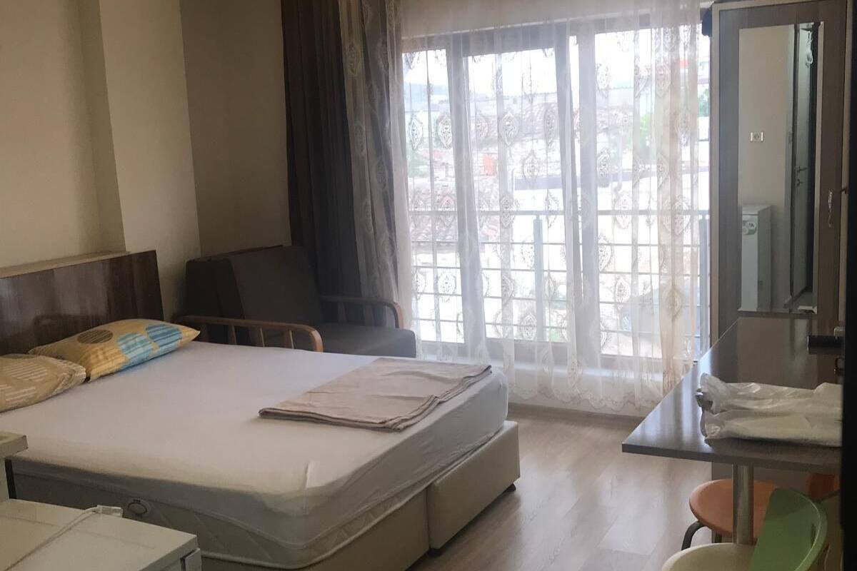 A hotel room with a bed, a desk, a chair, and a large window with curtains.