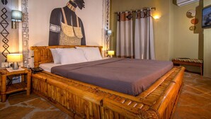 A room with a wooden bed, a wall mural, and a television. - Bamboo Village Resort (Serrekunda)